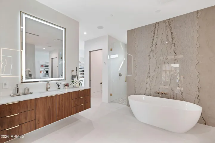 Luxurious primary bathroom featuring a freestanding tub, floating vanity, LED mirror, and walk-in glass shower. This Paradise Valley home highlights modern finishes, clean lines, and a spa-like atmosphere.