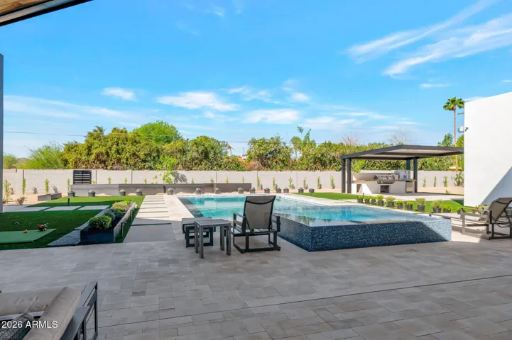Beautiful pool area with lounging space, clean lines, and modern landscaping. This Paradise Valley home offers a private backyard retreat with updated outdoor features.