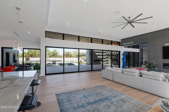 Stunning living room with floor-to-ceiling glass doors showcasing seamless indoor-outdoor living and views of the pool area. This Paradise Valley home features modern design, natural light, and energy-efficient window systems.