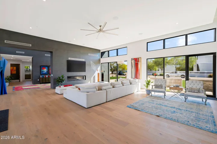 Sunlit living area with expansive windows and open floor plan, offering views of the landscaped front yard. This Paradise Valley home emphasizes indoor-outdoor living and modern comfort.