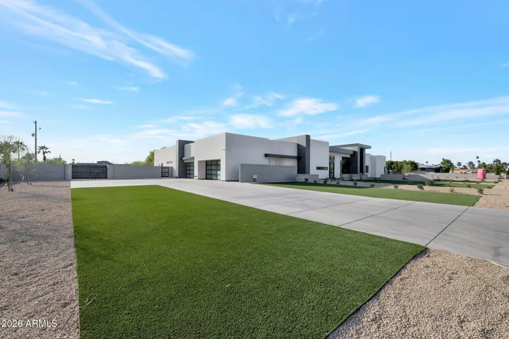 Wide south-facing view of the Paradise Valley property showcasing an extended driveway, manicured lawn, and modern architecture. The spacious lot offers privacy, clean landscaping, and impressive curb appeal.