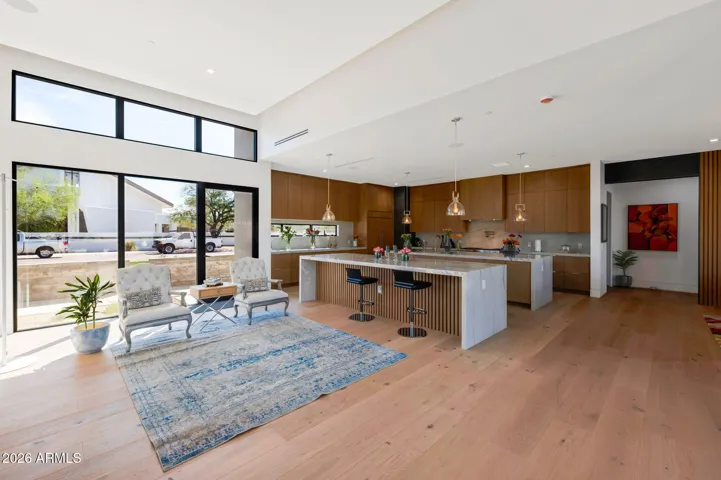 Elegant living space featuring soaring ceilings, large windows, and open flow into the gourmet kitchen. This Paradise Valley home offers a luxurious and inviting atmosphere.