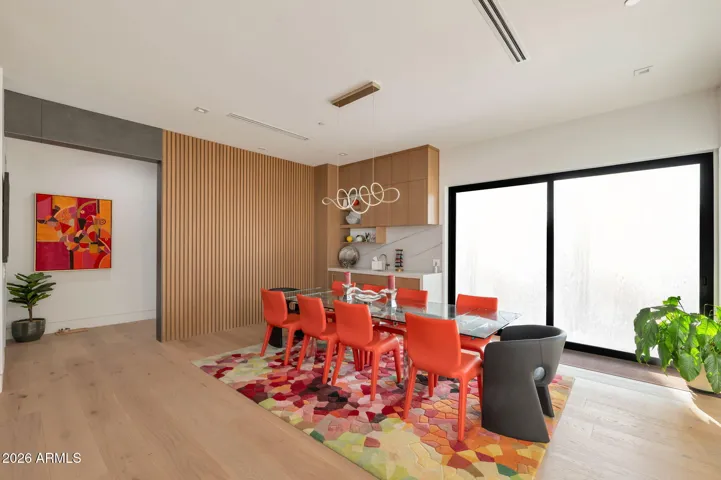 Stylish dining room with contemporary lighting, custom wall accents, and large sliding glass doors. This Paradise Valley home offers a perfect space for entertaining with modern design elements. The picture was taken prior to the custom display case was installed
