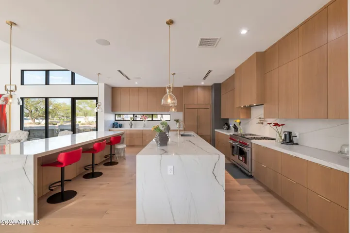 Modern kitchen with a large waterfall island, custom cabinetry, and premium appliances. This Paradise Valley home showcases high-end finishes and an open layout perfect for entertaining.