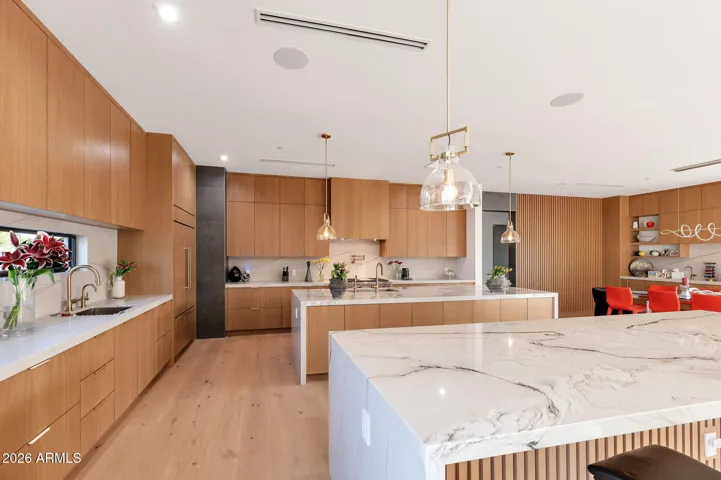 Stunning chef’s kitchen with dual quartz waterfall islands, custom cabinetry, and designer lighting. This Paradise Valley home offers luxury finishes, open-concept design, and ideal functionality for entertaining.