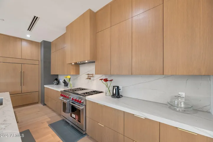 Sleek kitchen cabinetry with warm wood finishes, quartz countertops, and built-in appliances. This Paradise Valley home features modern design, premium materials, and a chef-inspired layout.