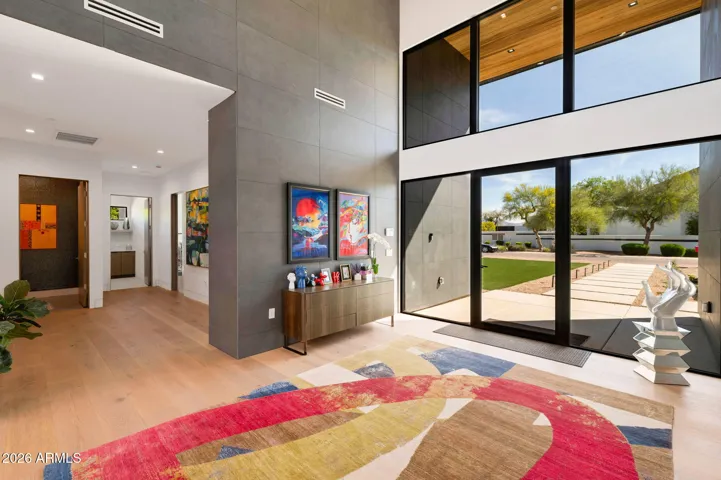 Bright front living area with soaring ceilings, oversized windows, and seamless flow into the main living spaces. This Paradise Valley home highlights modern design and natural light throughout.