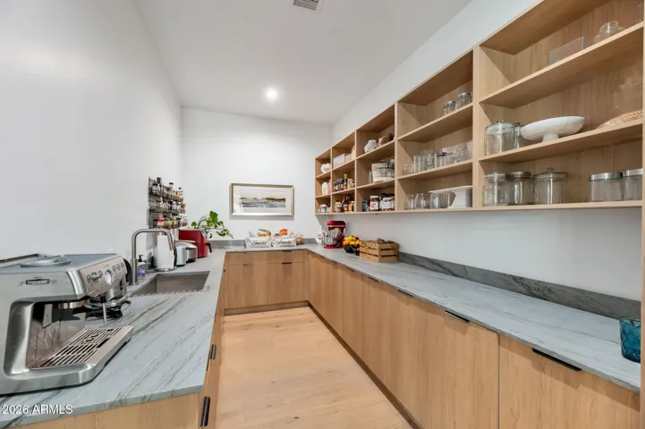Spacious walk-in pantry with custom shelving, ample storage, and prep space. This Paradise Valley home offers functional organization and modern convenience for everyday living.