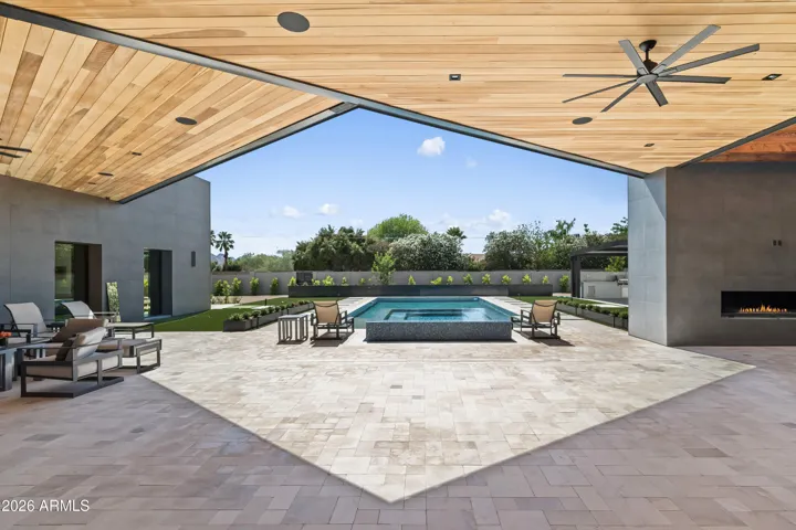 Expansive covered patio in Paradise Valley featuring wood ceiling details, and seamless views of the resort-style pool. Designed for indoor-outdoor living, this space is perfect for entertaining and relaxing year-round.