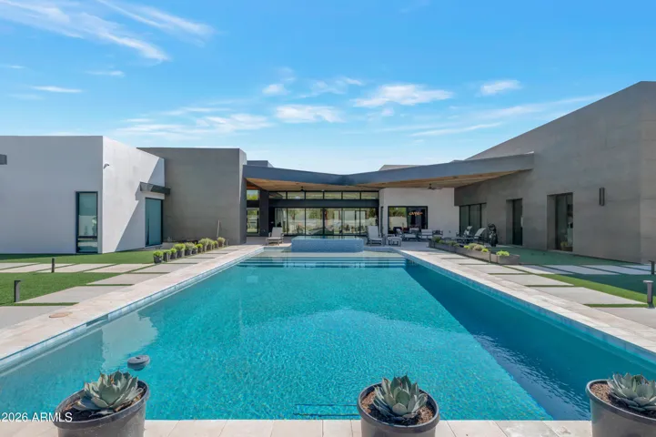 Expansive resort-style pool with clean modern lines, surrounded by desert landscaping and multiple lounge areas. This Paradise Valley outdoor space offers luxury living, privacy, and ideal entertaining.