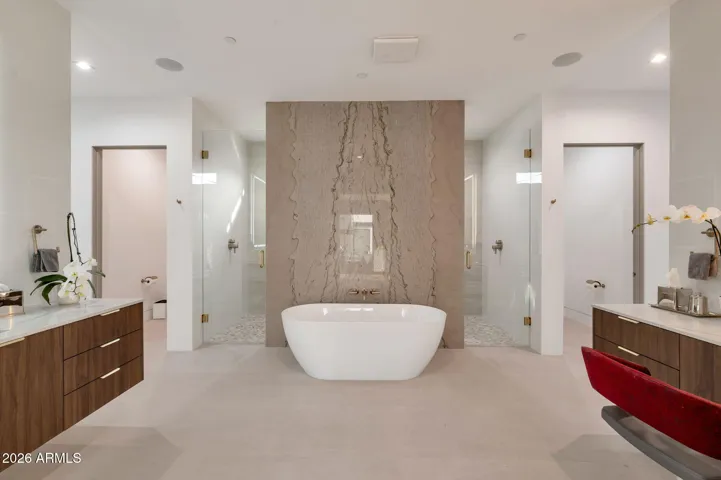 Elegant spa-style primary bathroom in Paradise Valley featuring a freestanding soaking tub, floor-to-ceiling marble accent wall, dual vanities, and glass walk-in showers. This luxury bathroom showcases modern design, high-end finishes, and a serene retreat atmosphere.