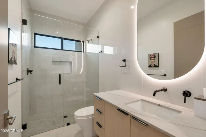 Stylish bathroom featuring a glass walk-in shower, floating vanity, and designer lighting. This Paradise Valley home includes updated finishes and a clean, contemporary look.