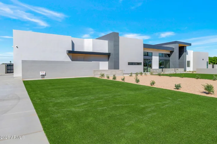 Wide-angle view of the landscaped front yard and modern exterior design. This Paradise Valley property features desert landscaping, clean lines, and a spacious estate setting.