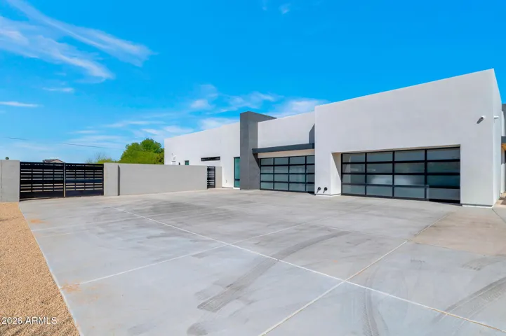 Large driveway with modern architecture and ample parking space leading to oversized garage. This Paradise Valley home offers functionality and curb appeal.