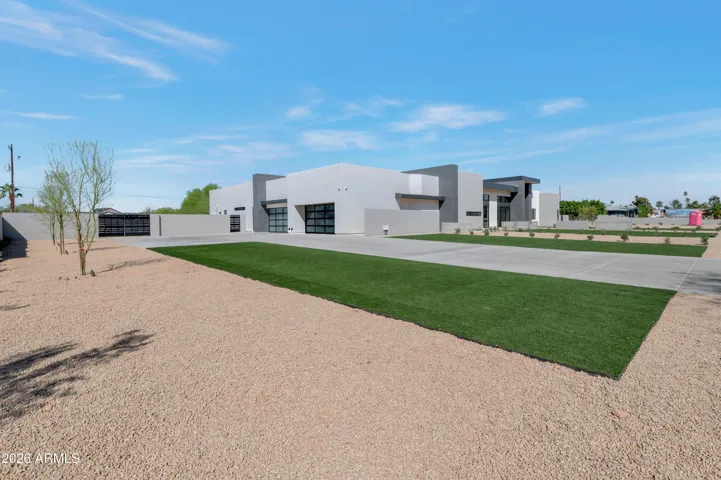 Side perspective of the landscaped front yard with desert gravel, lush turf, and contemporary exterior design. This Paradise Valley home features low-maintenance landscaping and a large estate setting.
