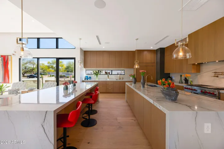 Side view of expansive kitchen with dual islands, modern lighting, and premium finishes. This Paradise Valley home combines style, function, and ample workspace.