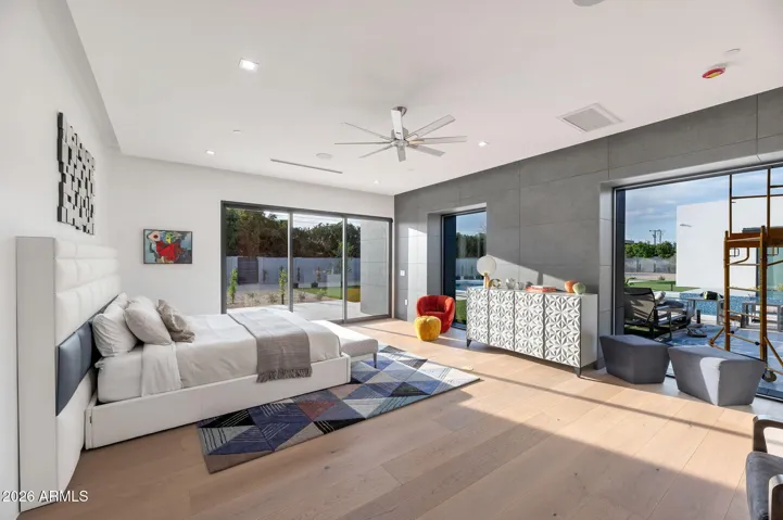 Large primary suite with oversized sliding glass doors, wood flooring, and seamless indoor-outdoor flow to the backyard and pool. This Paradise Valley estate offers comfort, natural light, and contemporary design.