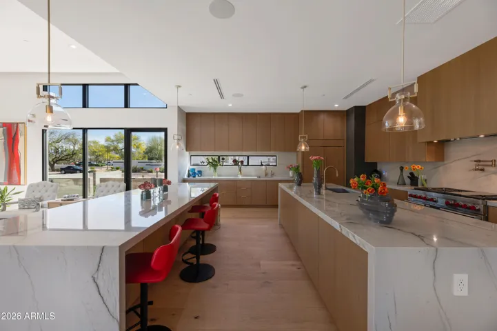 Modern kitchen featuring waterfall island, bar seating, designer lighting, and premium finishes. This Paradise Valley home blends elegance with functionality.