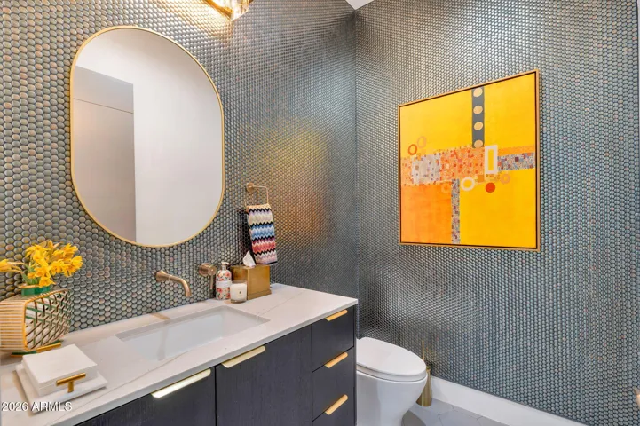 Stylish powder room with textured accent walls, modern vanity, and statement mirror. This Paradise Valley home features high-end finishes and unique design details throughout.