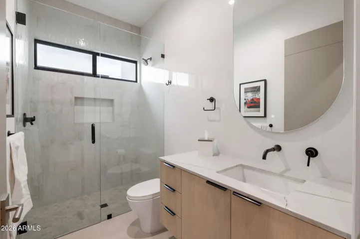 Stylish bathroom with glass walk-in shower, sleek vanity, and updated fixtures. This Paradise Valley home features contemporary finishes and functional design.