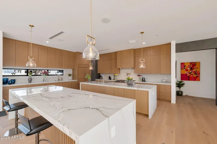 Gourmet kitchen featuring dual waterfall islands, custom cabinetry, premium appliances, and sleek pendant lighting. This Paradise Valley luxury kitchen is designed for entertaining, offering ample prep space and modern elegance.