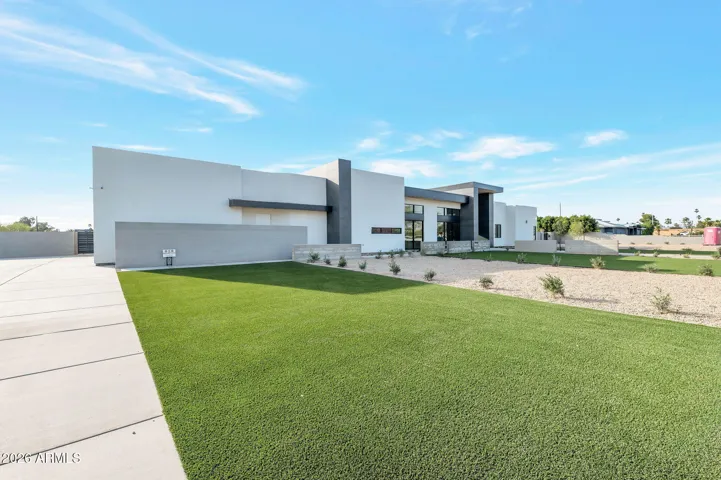 Daytime exterior showcasing the clean modern lines, expansive lot, and landscaped grounds. This Paradise Valley home offers a private estate feel with contemporary design and desert landscaping.