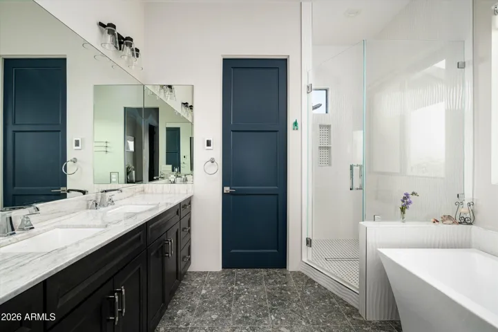 This primary bathroom offers a fully tiled walk-in shower along with dual vanities and a separate tub.