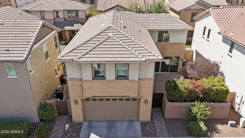 Back of this 2-story home with a 2-car garage and gate to a private paver patio.