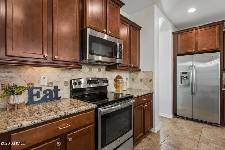 Warm cabinetry with 42" uppers, granite countertops, stone backsplash