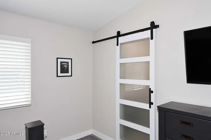 Barn door separates primary bedroom from bath