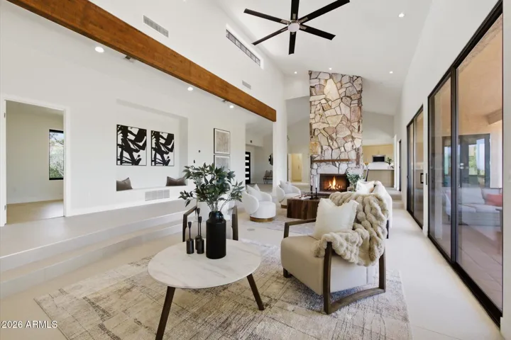 Elegant living room featuring a majestic stone fireplace, soaring ceilings, and a sense of refined spaciousness.