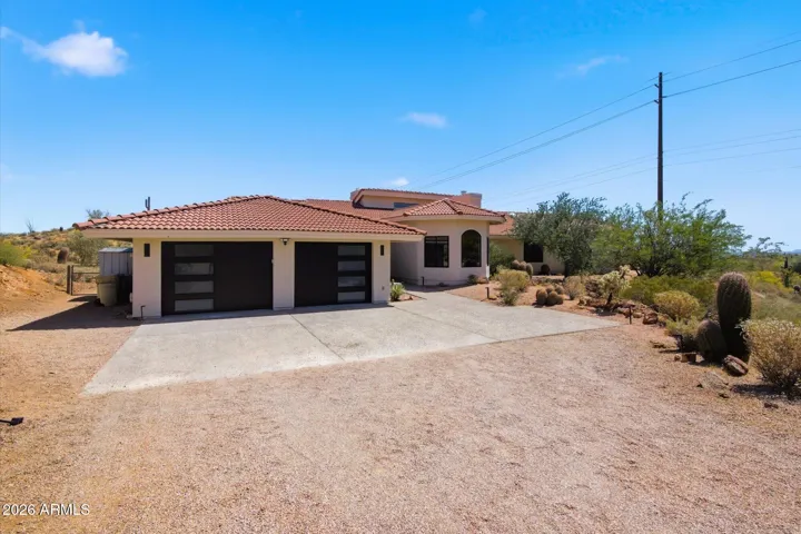 Front exterior of the home, featuring a modern garage and ample driveway space, set against the desert backdrop.