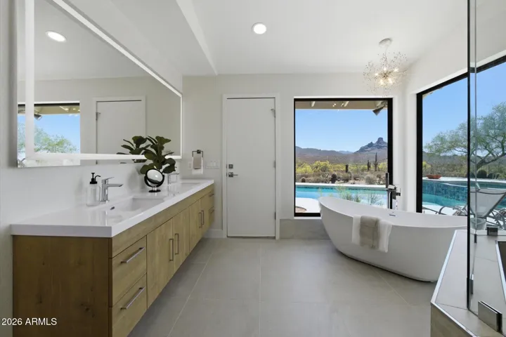 Elegant en-suite bathroom with a spacious dual vanity, modern fixtures, and picturesque views of the private outdoor oasis.