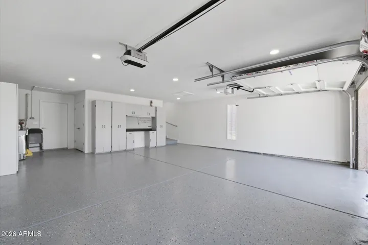 Expansive and well-lit oversized 2.5 car garage, featuring ample storage cabinetry and a clean, organized space.