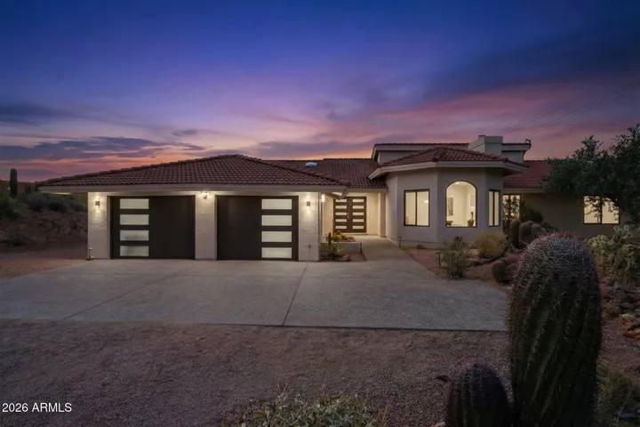 Striking front exterior of the home at dusk, showcasing modern garage doors and inviting entrance against a colorful sky.