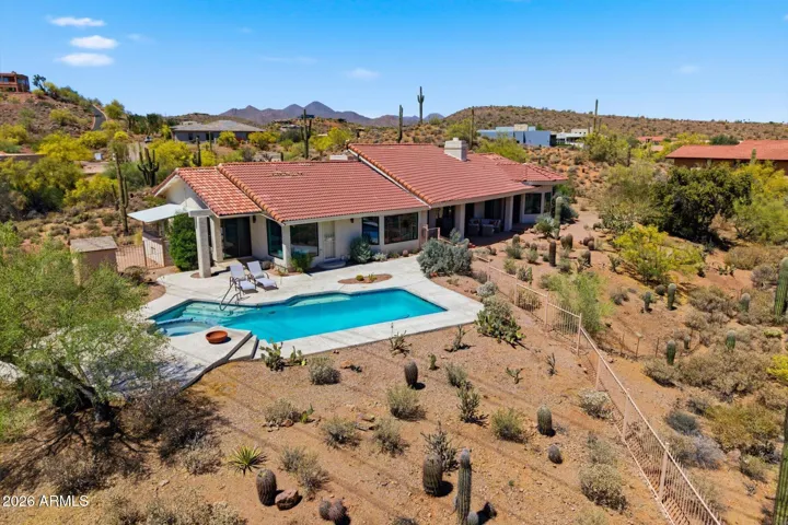 Aerial perspective revealing the home's impressive exterior, featuring a sparkling pool, and panoramic views of the expansive desert.