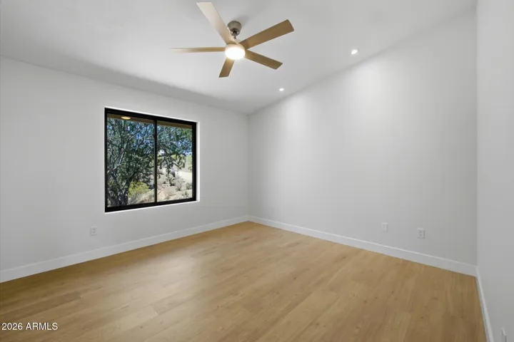 Peaceful secondary bedroom with a ceiling fan, abundant natural light, and a serene view of the natural surroundings.