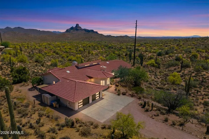 Panoramic aerial view of the property at twilight, highlighting the home, pool, and expansive desert landscape with distant mountains.