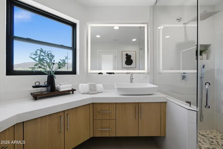 Sophisticated guest bathroom with a chic vanity, illuminated mirror, and picturesque desert views through the window.