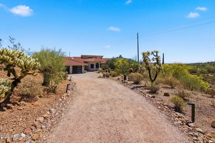 Scenic approach to the property, showcasing the home nestled within the natural desert landscape.