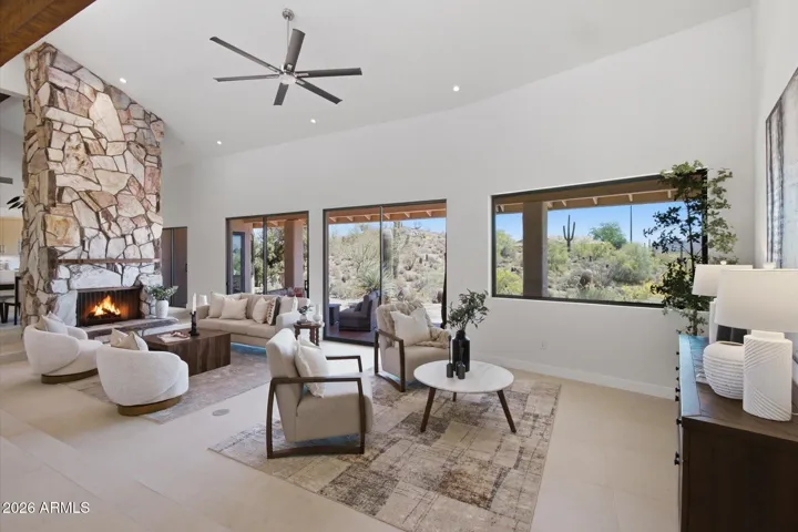 Bright and airy living room offering stunning desert views and a cozy fireplace, ideal for relaxation and entertaining.
