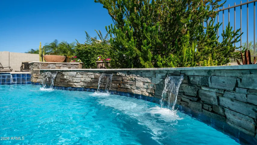 A Stunning Stone Water Feature Enhances the Poolside Ambiance