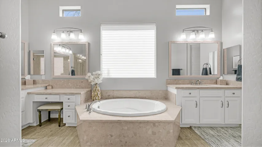 A Spa Like Soaking Tub Framed by Dual Vanities and Natural Light