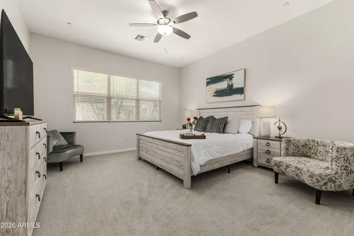 Spacious primary suite with tranquil views, 10-ft ceilings, and soft natural light. Features plush carpeting, modern ceiling fan, and ensuite bath with dual vanities, soaking tub, and walk-in shower for a spa-like retreat.