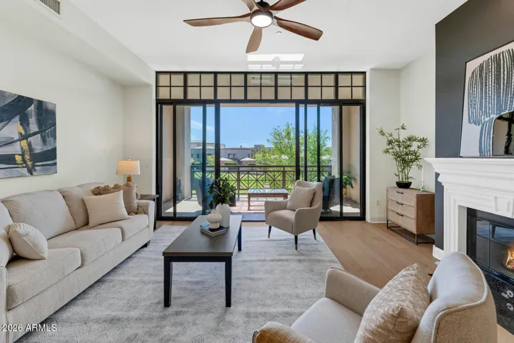 Light-filled living room with elegant finishes, a cozy fireplace, and dramatic floor-to-ceiling windows that open to a private balcony overlooking the lush fairways of the Arizona Biltmore Golf Club.