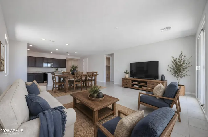 Large great room with tile flooring, recessed lighting, and backyard access. This open space in Buckeye is perfect for relaxing, entertaining, and flexible living arrangements.