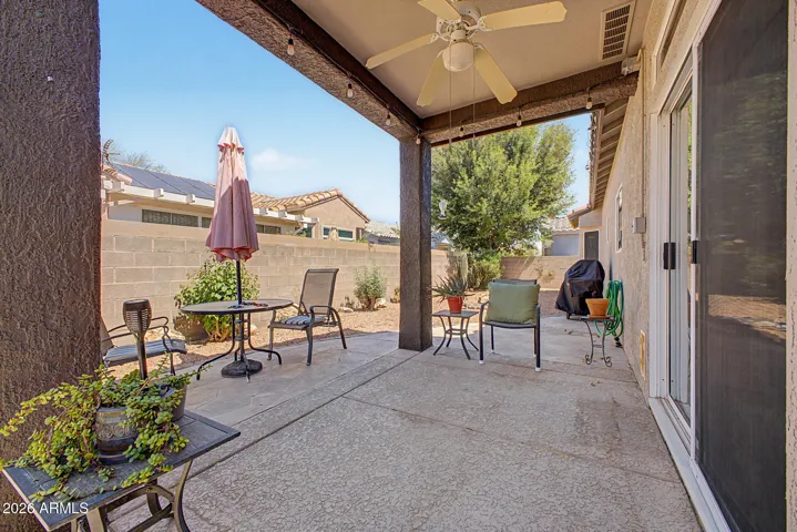 Cozy backyard with paved, covered patio and ceiling fan.