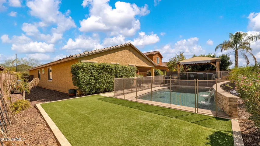 Pebble Tec pool with cascading water features shown with removable safety fence, offering flexibility for everyday safety and easy removal when entertaining.