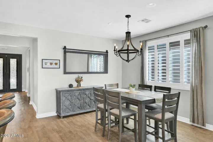Defined dining space with custom lighting and plantation shutters, offering a comfortable setting for everyday meals or more formal gatherings.