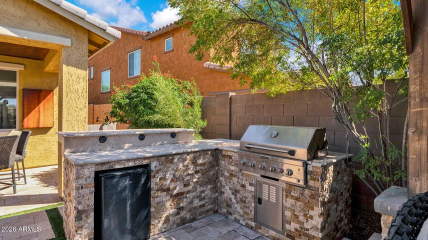Built-in outdoor kitchen with BBQ and bar area, creating a dedicated space for cooking, gathering, and entertaining in the backyard.